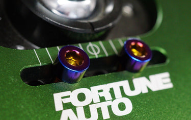 Close-up of Oil Slick titanium camber top plate bolts installed on a Fortune Auto coilover camber plate